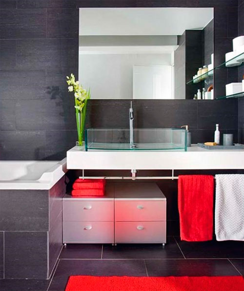 Красные полотенца в ванной комнате, оформленной в сером цвете, очень оживляют интерьер